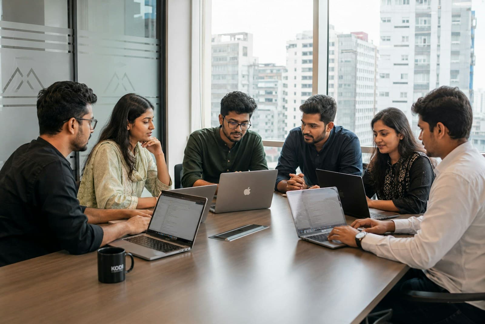 Professional team collaborating around laptops for a software house versus freelancer comparison